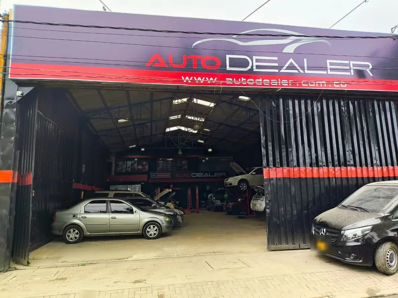 Fachada de la sede Cali con aviso Auto Dealer y portón abierto