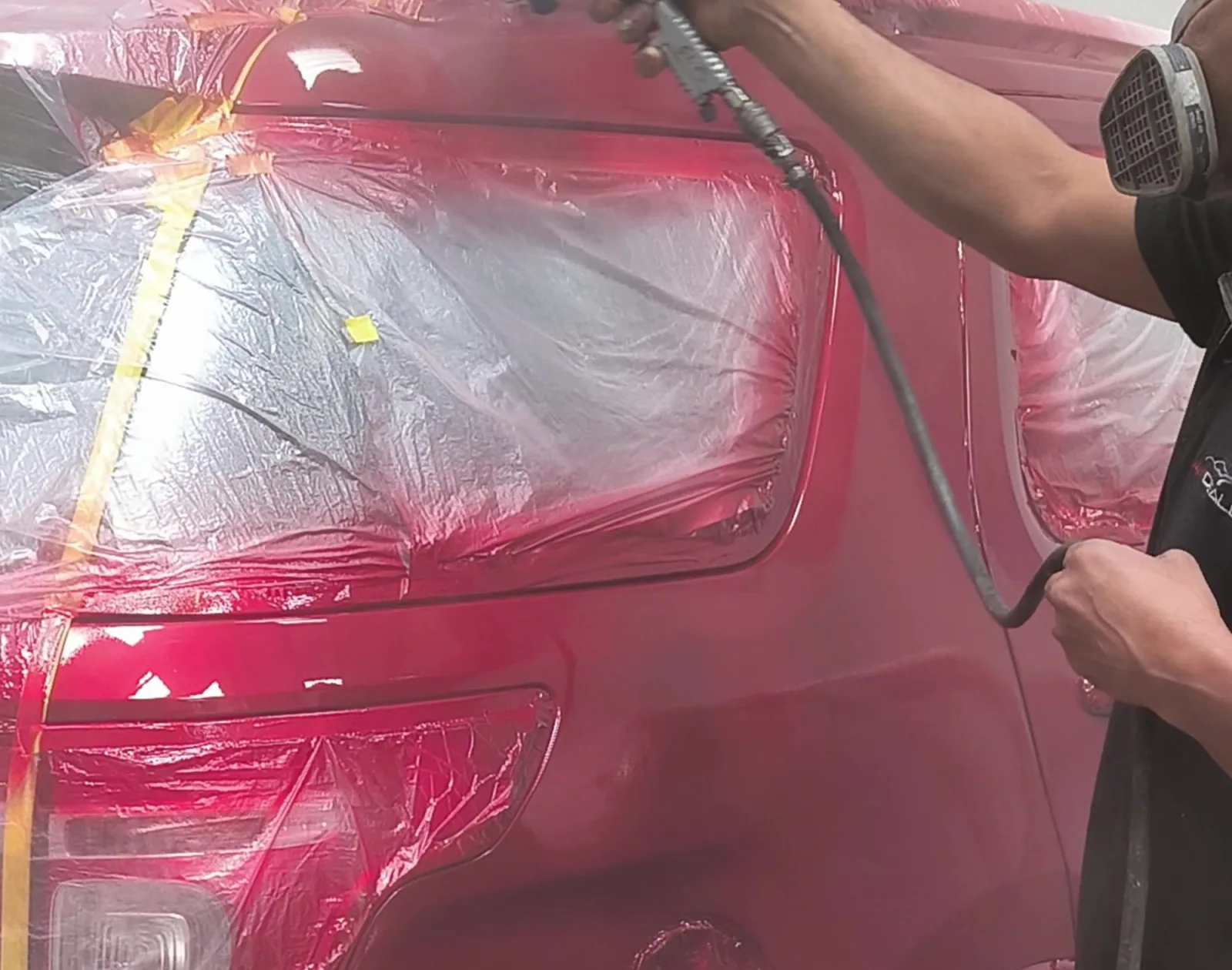 Técnico aplicando pintura automotriz con pistola